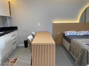 a small bedroom with a bed and a wooden desk at LINDO LOFT 350m Vila Germânica in Blumenau +13 photos