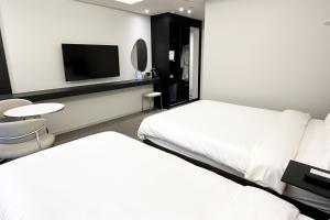 a hotel room with two beds and a flat screen tv at 코브스테이 해운대 in Busan