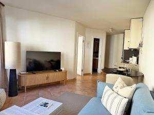 a living room with a blue couch and a flat screen tv at Zentrale Oase, Ski, Berge Spass, 45m2, für 2P - C8 in St. Moritz