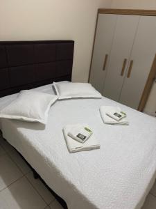Una cama blanca con dos toallas encima. en Residencial lara 101, en Itapema