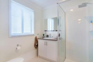 a white bathroom with a shower and a sink at Isla Bonita - Pet Friendly - Not Fully Fenced - No Linen Included in Hindmarsh Island