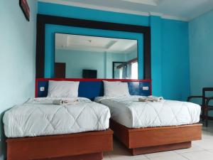 una camera blu con due letti e uno specchio di Citepus Indah Hotel a Citepus Altre 2 foto