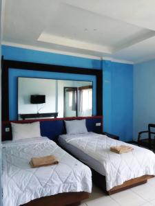 2 letti in una camera con parete blu di Citepus Indah Hotel a Citepus