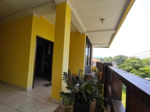 a building with yellow walls and a balcony with plants at Citepus Indah Hotel in Citepus