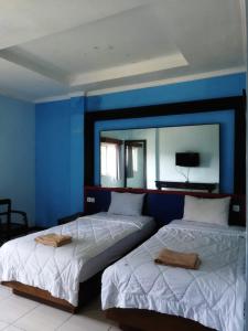 2 letti in una camera con parete blu di Citepus Indah Hotel a Citepus