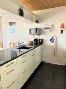 a kitchen with white cabinets and a black counter top at Stockenmatt Haus 2, Wohnung 22 in Stalden +7 photos