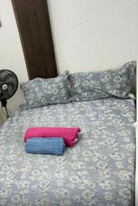 a bed with two pillows and a pink pillow on it at Kitnet Dream House 1 in Bayeux