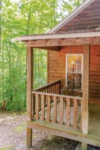 a wooden cabin with a porch in the woods at Rustic Cabin on 28-Acre Property in the Foothills of the Blue Ridge Mountains in Elkin