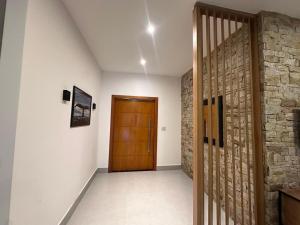 a hallway with a wooden door and a stone wall at Casa térrea moderna em condomínio in Bertioga