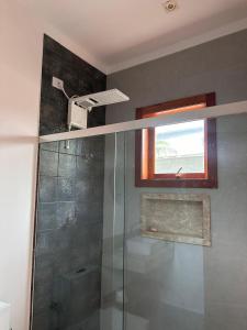 a bathroom with a glass shower with a window at Casa térrea moderna em condomínio in Bertioga +8 photos