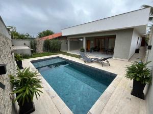 a swimming pool in front of a house at Casa térrea moderna em condomínio in Bertioga