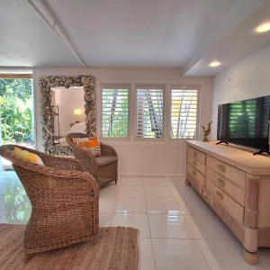a living room with a television and wicker chairs at Studio Casablanca in Nelly Bay