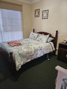 a bedroom with a bed with a floral comforter and a window at Murray's Bed & Breakfast in Gnowangerup