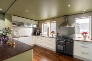 a kitchen with white cabinets and a black stove top oven at ARCTIC HOMES - The Spacious Villa in Tromsø