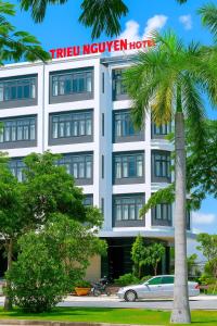 Tân UyênにあるTriệu Nguyễn Hotelのヤシの木が目の前にあるホテル