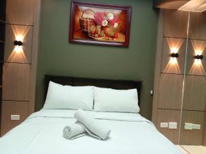 ein Schlafzimmer mit einem weißen Bett mit einem Bild an der Wand in der Unterkunft Cozy Manila Condo Retreat with Shared Pool in Manila + 2 Fotos