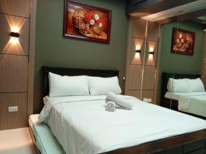 ein Schlafzimmer mit einem großen weißen Bett und einem Spiegel in der Unterkunft Cozy Manila Condo Retreat with Shared Pool in Manila