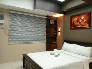 ein Schlafzimmer mit einem Bett mit einer Uhr an der Wand in der Unterkunft Cozy Manila Condo Retreat with Shared Pool in Manila