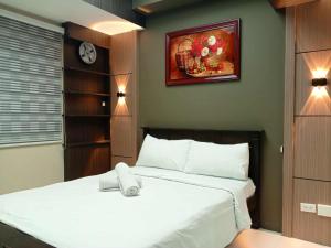 a bedroom with a white bed and a painting on the wall at Grand Riviera suites Manila Condo infront of us embassy in Manila