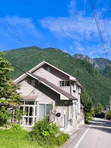 a house on the side of a road with a mountain at 山の湯 in Wada
