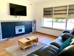 a living room with a couch and a fireplace at BeeJays Family Getaway in Kingscote