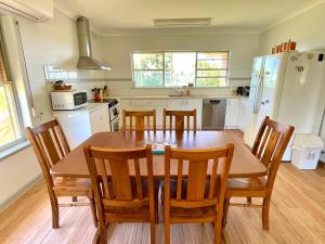 a kitchen with a wooden table and chairs and a kitchen with white appliances at BeeJays Family Getaway in Kingscote
