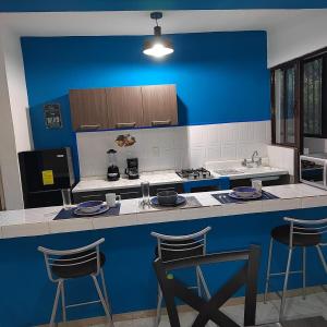 a blue and white kitchen with a counter and stools at Departamento Familiar Escorpións in Tuxtla Gutiérrez
