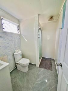 ein Badezimmer mit Toilette und Glasdusche in der Unterkunft Nuku'alofa Town Cottage - Private Double Room in Nuku‘alofa