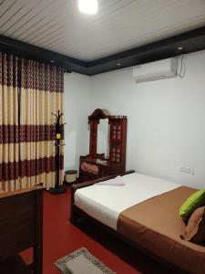 a bedroom with a bed and a mirror at Wilpattu Gagana guest in Nochchiyagama