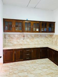 an empty kitchen with wooden cabinets and a tile floor at Ranathunga Guest House in Ginimellagaha West