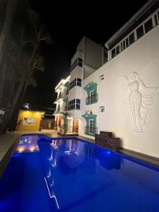 a swimming pool in front of a building at night at Luxus Resort in Puducherry