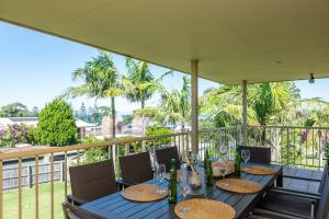una mesa con botellas de vino y copas en el balcón en Walk to the Beach in Central Location, en Mollymook