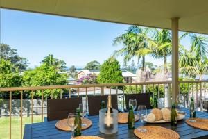 Una mesa azul con vasos y botellas de vino en un balcón en Walk to the Beach in Central Location, en Mollymook