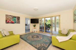Una sala de estar con dos sofás amarillos y una alfombra. en Walk to the Beach in Central Location, en Mollymook