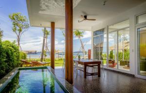 a dining room with a table and a swimming pool at Koh Apikjun Resort by EHM in Kaoh Sdach