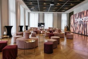 een grote kamer met stoelen en tafels en een podium bij Rosa Grand Milano - Starhotels Collezione in Milaan