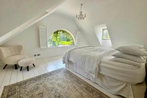 a white bedroom with a bed and a chair at Elegant Hampshire Countryside Stay in Petersfield