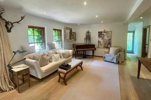 a living room with a white couch and a piano at Elegant Hampshire Countryside Stay in Petersfield +55 photos