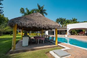 una mesa y sillas bajo una sombrilla de paja junto a una piscina en Large House with Pool in Yautepec, 4 Bedrooms, en Yautepec