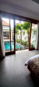 a bedroom with a view of a swimming pool through a sliding glass door at La Reina villa in Ubud