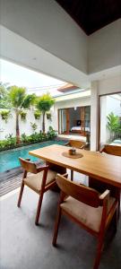a dining room with a large wooden table and chairs at La Reina villa in Ubud