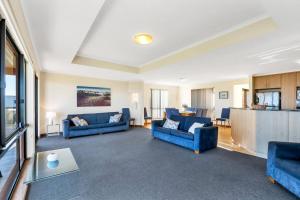 a living room with two blue couches and a kitchen at Coast View - 39b Hargreaves - Family - Beach - No Linen Included in Middleton