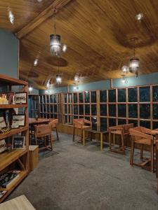 a room with wooden tables and benches and windows at HimWanderer Camps & Cottages Pangot in Nainital