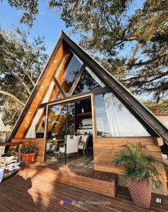 a small house with a large window on a deck at A-Frame da Lagoa in Imaruí
