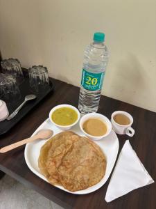 a table with a plate of food and a bottle of water at Hotel East park Electronic City in Bengaluru