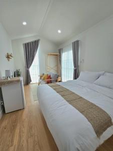 a large white bed in a room with windows at Waveway bangsaen 1 in Ban Thai Don (2)