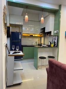 a kitchen with green cabinets and two bar stools at Hideaway Nest in Ghaziabad +3 photos