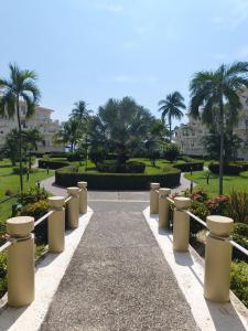 einen Gehweg in einem Park mit Palmen und Gebäuden in der Unterkunft Frente al Mar totalmente remodelado para 6 personas in Ixtapa
