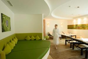 a woman walking through a living room with a green couch at Hotel Sonnblick in Gaschurn