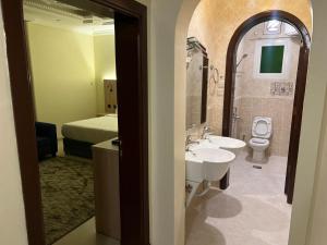 a bathroom with a sink and a toilet and a bed at أجنحة أحد للشقق المفروشة in Al Madinah